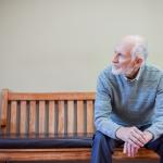 Older white man sitting indoors bench